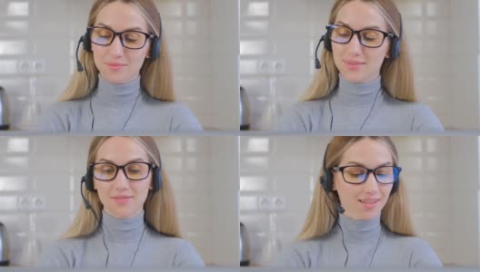 友好的呼叫中心话务员女士通过耳机通话。漂亮的白人女性，戴着眼镜，在笔记本电脑的网络摄像头上与客户交谈。帮助台专家在封锁期间在家工作高清在线视频素材下载
