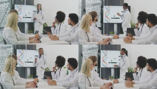 有吸引力、有目的、有经验的黑皮肤医生站在互动屏幕附近，在国际医学同事面前介绍人体内部器官的报告高清在线视频素材下载