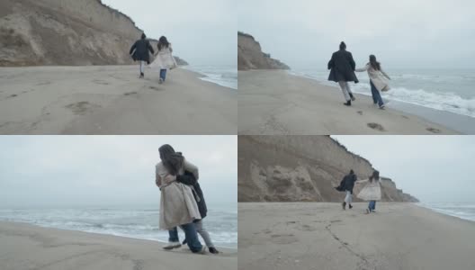 在多云的日出中，一对快乐的情侣在狂野的海滩上奔跑高清在线视频素材下载