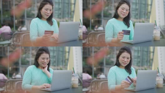 微笑的亚洲妇女使用智能手机和信用卡管理网上银行，坐在阳台花园的夜光。网上购物让生活更容易，生活方式和技术高清在线视频素材下载