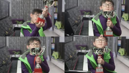 拿着银质奖杯的男孩在钢琴旁高清在线视频素材下载