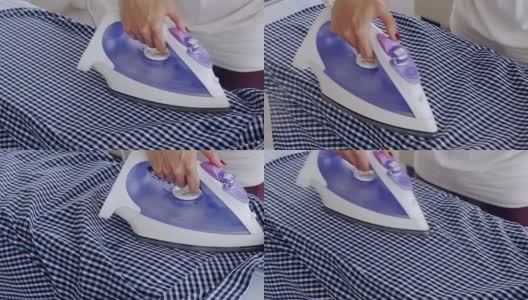 Skinny female hands ironing checked shirt高清在线视频素材下载