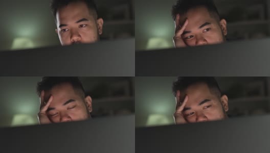 亚洲男人在家里使用电脑工作到很晚时，感觉不开心，有压力和疲倦。高清在线视频素材下载