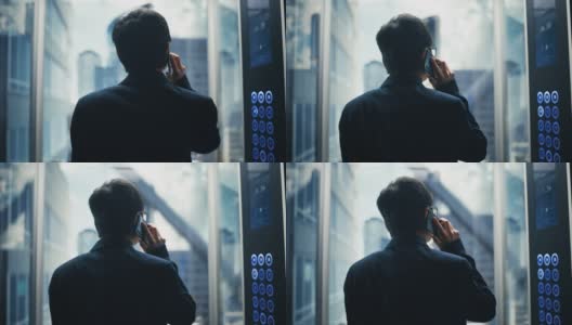 成功时尚的日本商人乘坐玻璃电梯到现代商务中心的办公室。英俊快乐的男人在打电话，在电梯里接一个重要的商务电话。高清在线视频素材下载