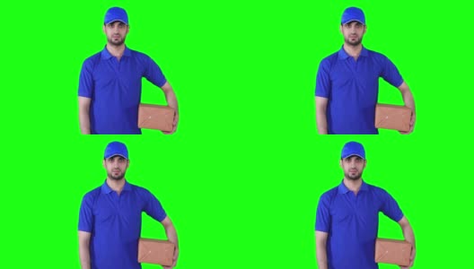 年轻男性快递员拿着一个包裹，在前面的绿色屏幕背景上竖起大拇指高清在线视频素材下载