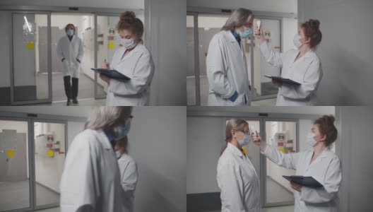 医护人员戴着安全口罩，用红外体温计测量员工体温高清在线视频素材下载