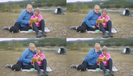 快乐的老年夫妇在树林露营时看书-老年人旅行的生活方式高清在线视频素材下载