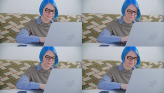 专注的年轻女子在电脑上打字。美丽的女性染成蓝色的头发工作在家里的4k股票视频剪辑笔记本电脑。千禧一代在笔记本电脑和互联网上做远程自由职业高清在线视频素材下载