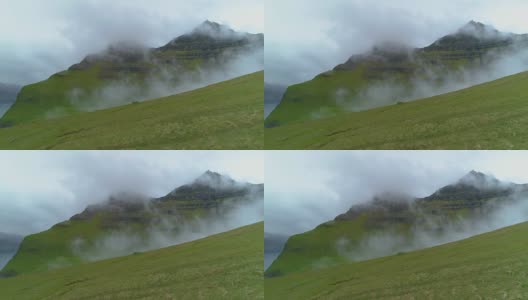 航拍:在雾天飞过空旷的草地，一直飞到长满青草的山上。高清在线视频素材下载