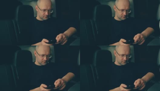 身穿毛衣的中年男子晚上在SUV后座上使用智能手机高清在线视频素材下载