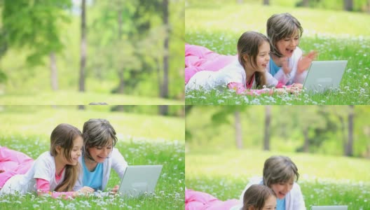 妈妈和女儿在电脑上打字，在公园里大笑。高清在线视频素材下载