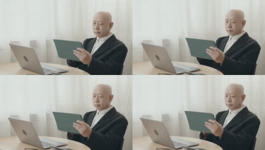 没有头发的亚裔中国高管在开放式办公室里用笔记本电脑打字高清在线视频素材下载
