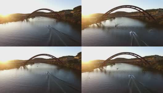 太阳闪光船在水Pennybacker桥或360桥或首都德克萨斯高速公路桥在日落在科罗拉多河或镇湖春天时间空中跟随一艘船在水加速进入阳光高清在线视频素材下载