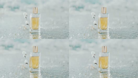 在一个结霜的池塘里，一个装着金色香水的长方形玻璃瓶伫立在白雪皑皑的树枝旁。香水和香水模板高清在线视频素材下载