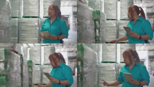 亚洲中国女性蓝领工人清点库存，在工厂仓库包装商品纸箱在托盘柜台上检查并记录在数字平板上准备出货高清在线视频素材下载