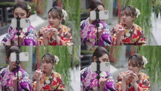 穿着和服的年轻女性朋友为了拍视频而吃街头小吃高清在线视频素材下载