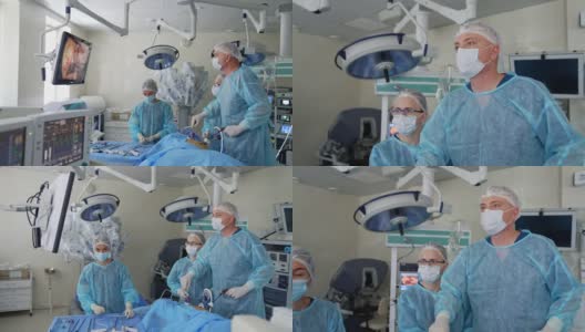主刀外科医生在手术中使用医疗设备，看着显示器显示病人的内部器官。两名医生协助主刀外科医生。技术在外科手术中的应用。高清在线视频素材下载