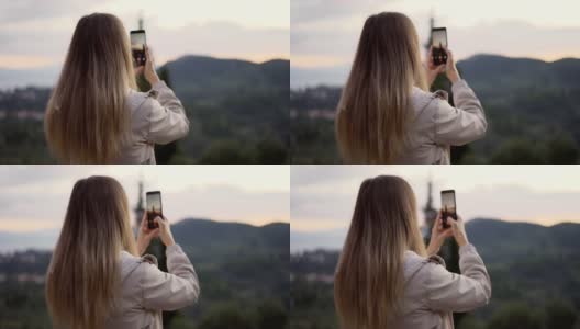 一名金发女子手持智能手机拍摄山景高清在线视频素材下载
