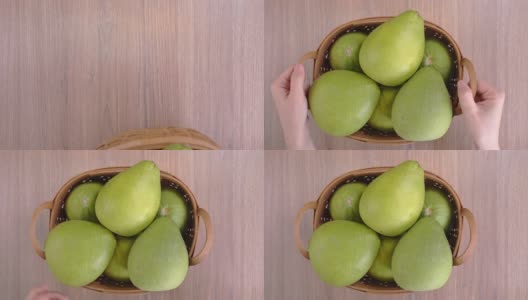 年轻的亚洲女子正抱着一篮子新鲜的柚子放在木桌上，以有机果园的秋收理念。影棚拍摄。高清在线视频素材下载