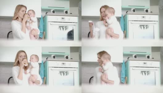 妈妈喝着咖啡，抱着小婴儿在厨房里。产假高清在线视频素材下载