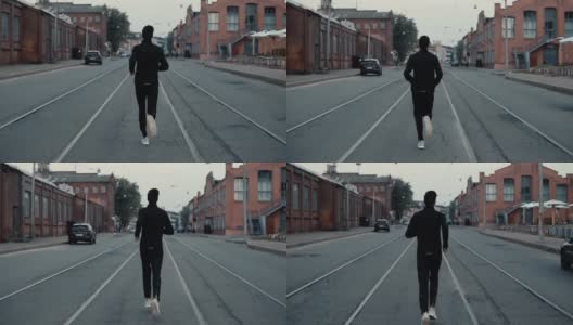 一个运动员在马路中间跑步。背景拍摄。缓慢的运动。回望电车轨道之间的远处景色高清在线视频素材下载