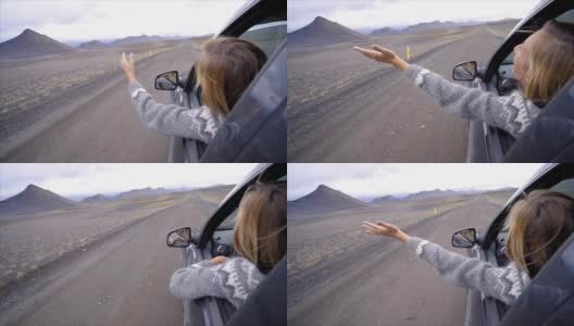 开朗的白种女性在车里看着路伸出双臂，山上火山景观。公路旅行的概念。金发女孩看着风景。慢动作高清在线视频素材下载