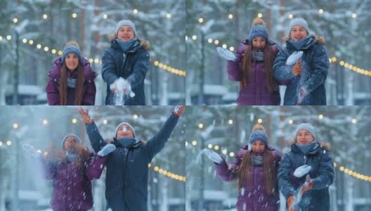 一对穿着夹克和帽子的有趣夫妇在冬天的公园里扔雪高清在线视频素材下载