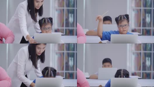 一名患有唐氏综合症的10岁亚洲女孩在小学课堂上举手，而年轻的女老师正在教室里教电脑。2019年残疾人募捐高清在线视频素材下载
