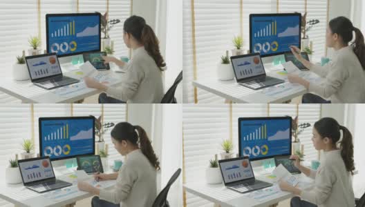 年轻有吸引力的亚裔泰国女性员工忙着在网上多屏幕笔记本电脑或智能平板电脑在家里自由销售数据分析，数据科学工程师的业务。高清在线视频素材下载
