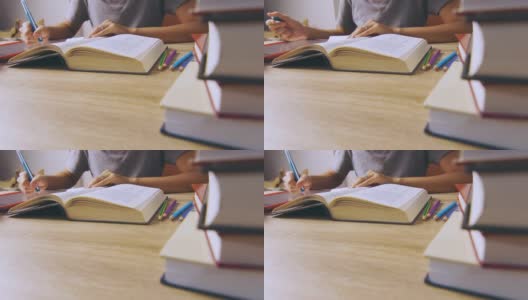 近距离偷拍的4K画面中，一名职业女性正全神贯注地在一堆书的桌前看书，展现了自学生活方式学习知识的理念。高清在线视频素材下载