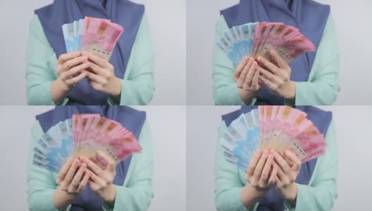 一名女子展示并摇晃着一叠印尼货币高清在线视频素材下载