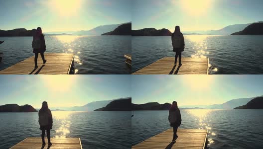 一个女人走在木码头上的湖边高清在线视频素材下载