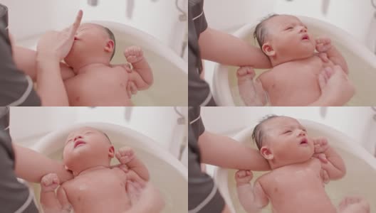 平静的亚洲新生儿沐浴在浴缸。母亲用温水给儿子洗澡。可爱的新生儿微笑在浴缸放松和舒适。新生儿护理理念高清在线视频素材下载