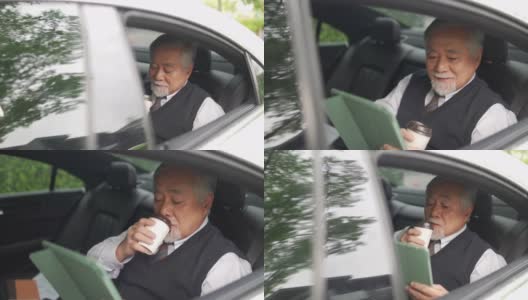 4K亚洲资深商人坐在汽车后座，一边喝着热咖啡，一边在数码平板电脑上工作高清在线视频素材下载