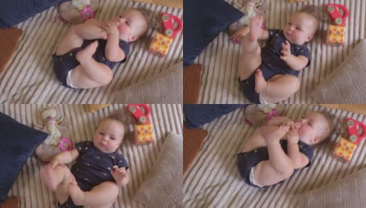 六个月大的婴儿把脚放进嘴里。良好的肌肉张力，屈曲连枷四肢。高清在线视频素材下载