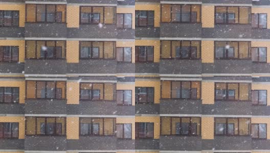 在一个大雪纷飞的冬天，城市里某公寓大楼的窗户前下起了一场大雪。雪花飘落得很快高清在线视频素材下载