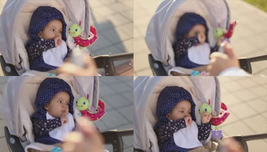 小女孩坐在婴儿车里，妈妈在公园里散步高清在线视频素材下载