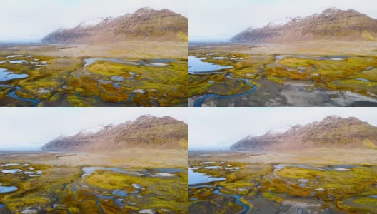 神奇的空中飞行在冰岛上空，从鸟瞰，这里是一片有着黄色苔藓和蓝绿色湖泊的火山景观。美丽而原始的自然高清在线视频素材下载