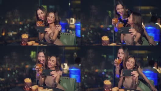 4K亚洲女性朋友晚上在屋顶餐厅吃饭时一起用智能手机自拍。高清在线视频素材下载