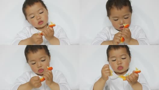 亚洲小孩认真地撕着橘子瓤，嘴唇抽动着高清在线视频素材下载
