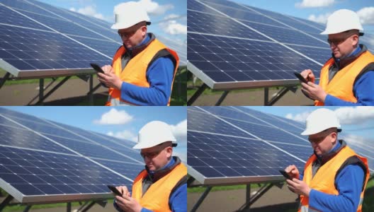 戴着头盔的男子在太阳能电池板的背景上使用智能手机。太阳能发电厂工人男性肖像高清在线视频素材下载