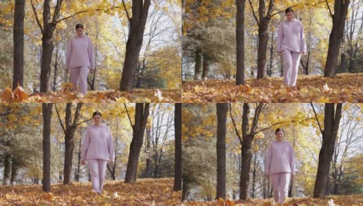 在秋天的森林里，一个女人走在枫叶飘落的地毯上高清在线视频素材下载