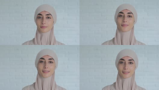 微笑的穆斯林妇女的肖像，戴着传统的希贾布头，看着自信的相机。一个阿拉伯女子的外表遵守伊斯兰世界和宗教的法律高清在线视频素材下载