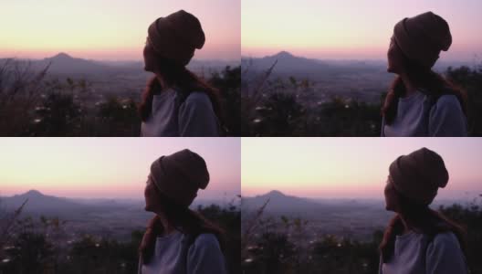 一个女游客在日出前看着美丽的山景的慢镜头高清在线视频素材下载