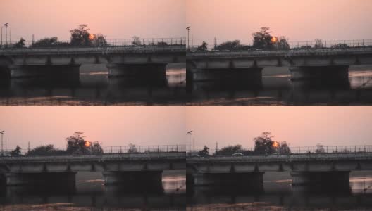 印度古吉拉特邦甘地那格的纳尔默达运河大桥的剪影。过桥车辆。桥在河水中的倒影，鸟儿在夜晚的天空中飞翔高清在线视频素材下载