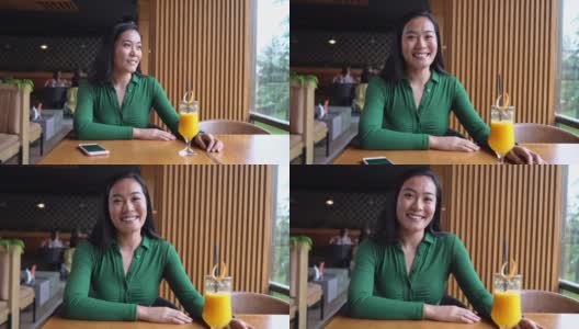 在现代的自助餐厅里，一个平静而无忧无虑的亚裔年轻女子的肖像高清在线视频素材下载