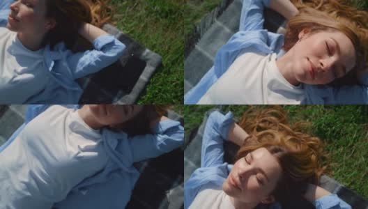 特写快乐的女孩躺在绿色的草地上。美丽的女人在户外享受阳光。高清在线视频素材下载