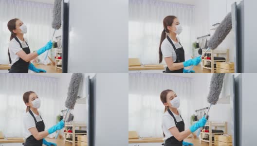 亚洲清洁服务女工清洁厨房和家庭。漂亮的女管家清洁工戴着口罩，用鸡毛掸子擦拭凌乱的柜台，为管家做家务或杂务。高清在线视频素材下载