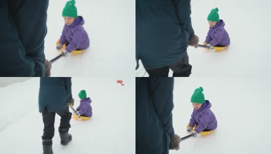在暴风雪中，波夫的父亲骑着他的小孩在乡村公路上铲雪。冬天，爸爸和儿子在后院铲雪。高清在线视频素材下载