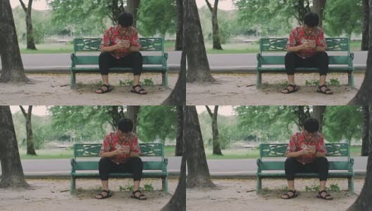 Cinemagraphs:年轻男子在公园使用智能手机。高清在线视频素材下载